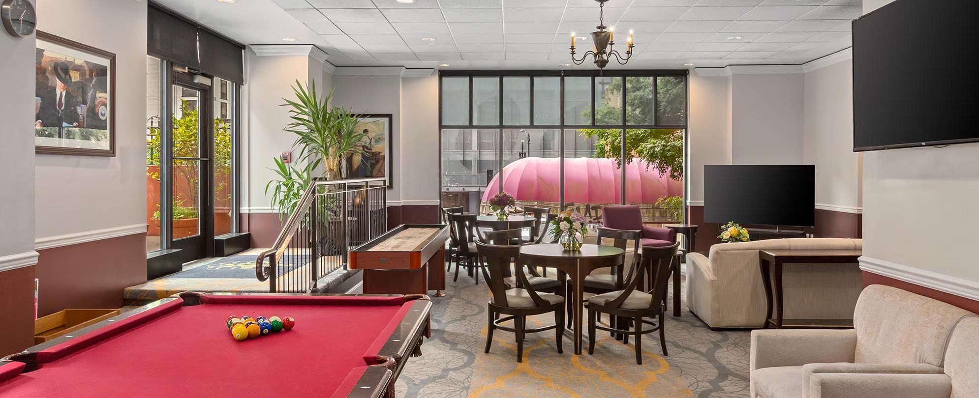 A billiards table, multiple chairs, a sofa, a television, and a large window with a view.