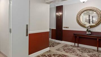 A hotel room with a washing machine, a mirror with an ornate frame, and a door with a number sign.