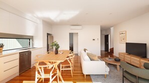 A modern apartment with a kitchen, dining area, living room, and a TV. - Cuthbert Place Broadmeadows (Broadmeadows)