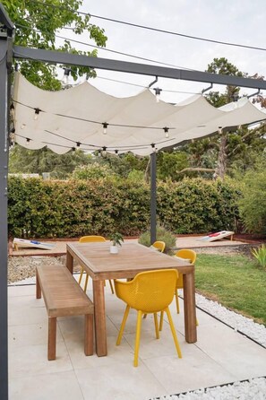 An outdoor patio with a wooden table and yellow chairs, surrounded by a white canopy. - Nature Lovers Casita! King Bed! Big Backyard (Fresno)
