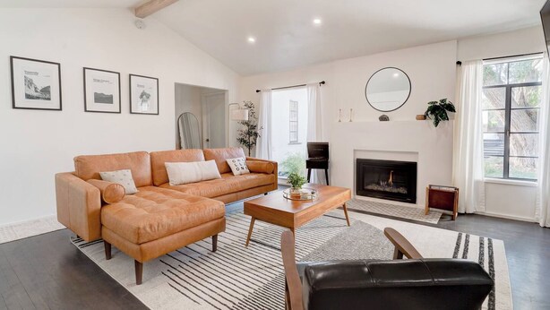 A living room with a sofa, coffee table, fireplace, and framed pictures on the wall.