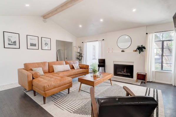 A living room with a sofa, coffee table, fireplace, and framed pictures on the wall.