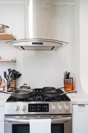 A kitchen with a gas stove, oven, and a stainless steel range hood. - Nature Lovers Casita! King Bed! Big Backyard (Fresno)