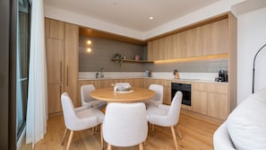A modern kitchen with wooden cabinets, a round dining table, and four chairs. - Horizon 95 - Melbourne (Melbourne)