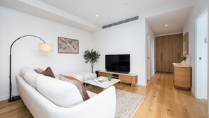 A modern living room with a sofa, a coffee table, a TV, and a floor lamp. - Horizon 95 - Melbourne (Melbourne)