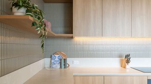A modern kitchen with a wooden countertop, a hanging plant, and a tiled backsplash. - Horizon 95 - Melbourne (Melbourne)