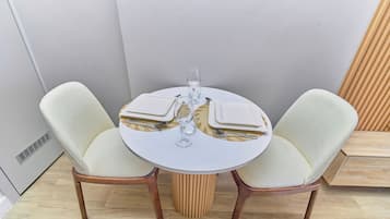 A round dining table with two chairs, a glass of water, and cutlery.