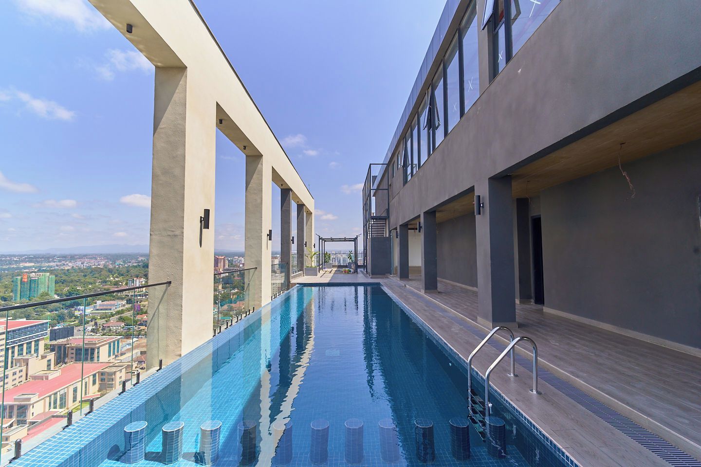 A rooftop infinity pool with a city view, surrounded by modern architecture.