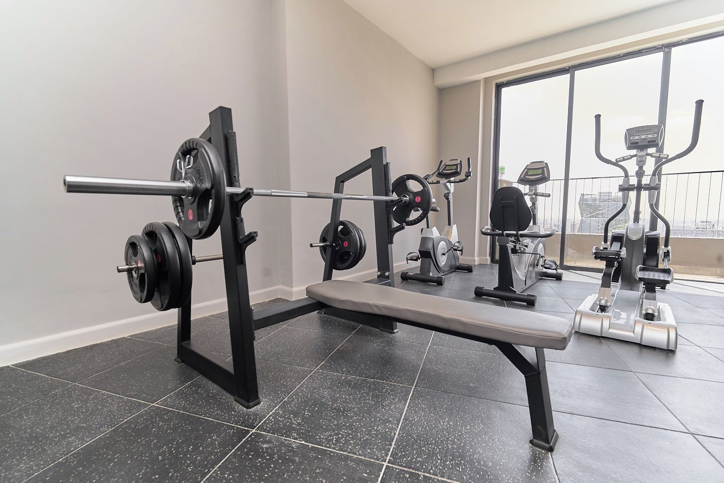A gym with a bench press, weight bench, and cardio machines.