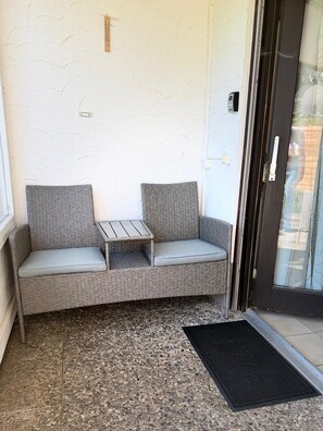 A corner seating area with a cushioned bench and a small table, a doormat, and a door with a handle. - A Natural Paradise in Herrenschwand. (Todtnau)