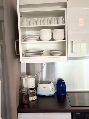 Una cocina con armarios blancos, una tostadora, una cafetera y un tarro de mermelada.