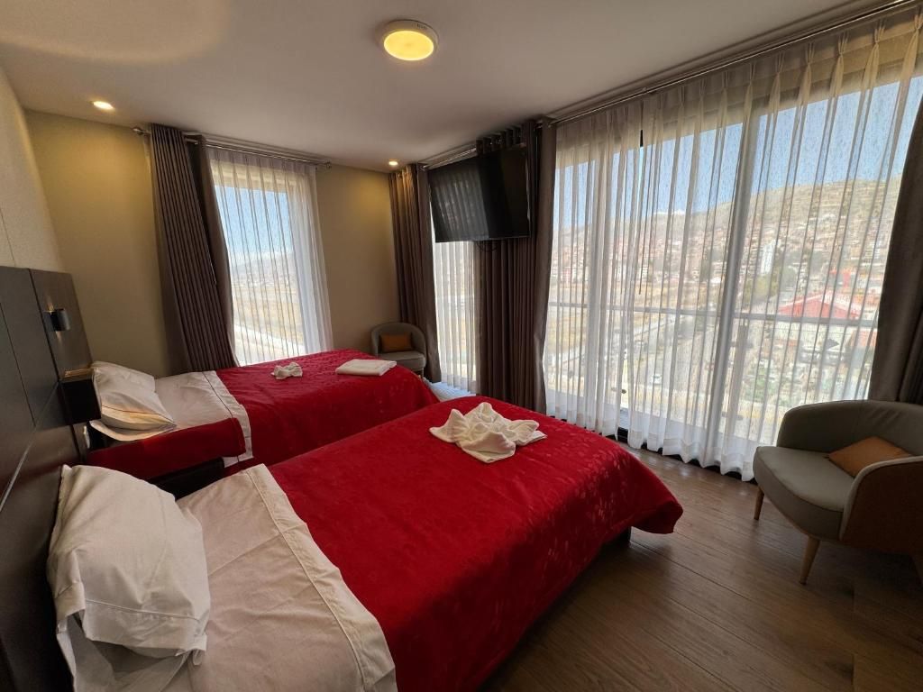 Habitación de hotel con dos camas, televisión, sofá y vistas a la ciudad.