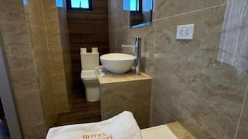 Une salle de bain avec une baignoire, un lavabo et des toilettes. Une serviette portant l’inscription « HÔTEL SAN MIGUEL » est posée sur la baignoire.