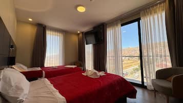 Quarto de hotel com duas camas, televisão e varanda com vista.