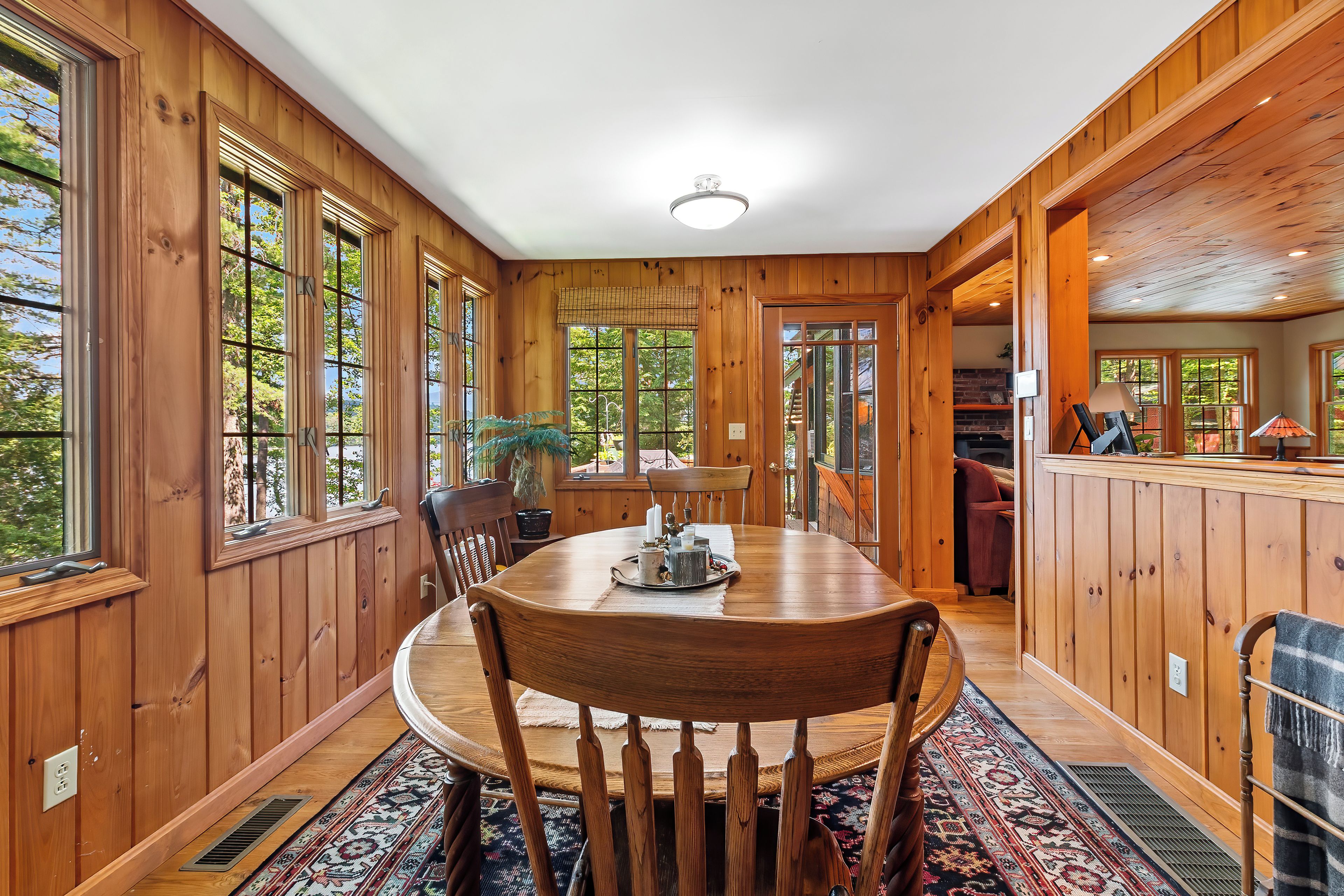 A wooden interior with a dining table, chairs, and a view through the windows.