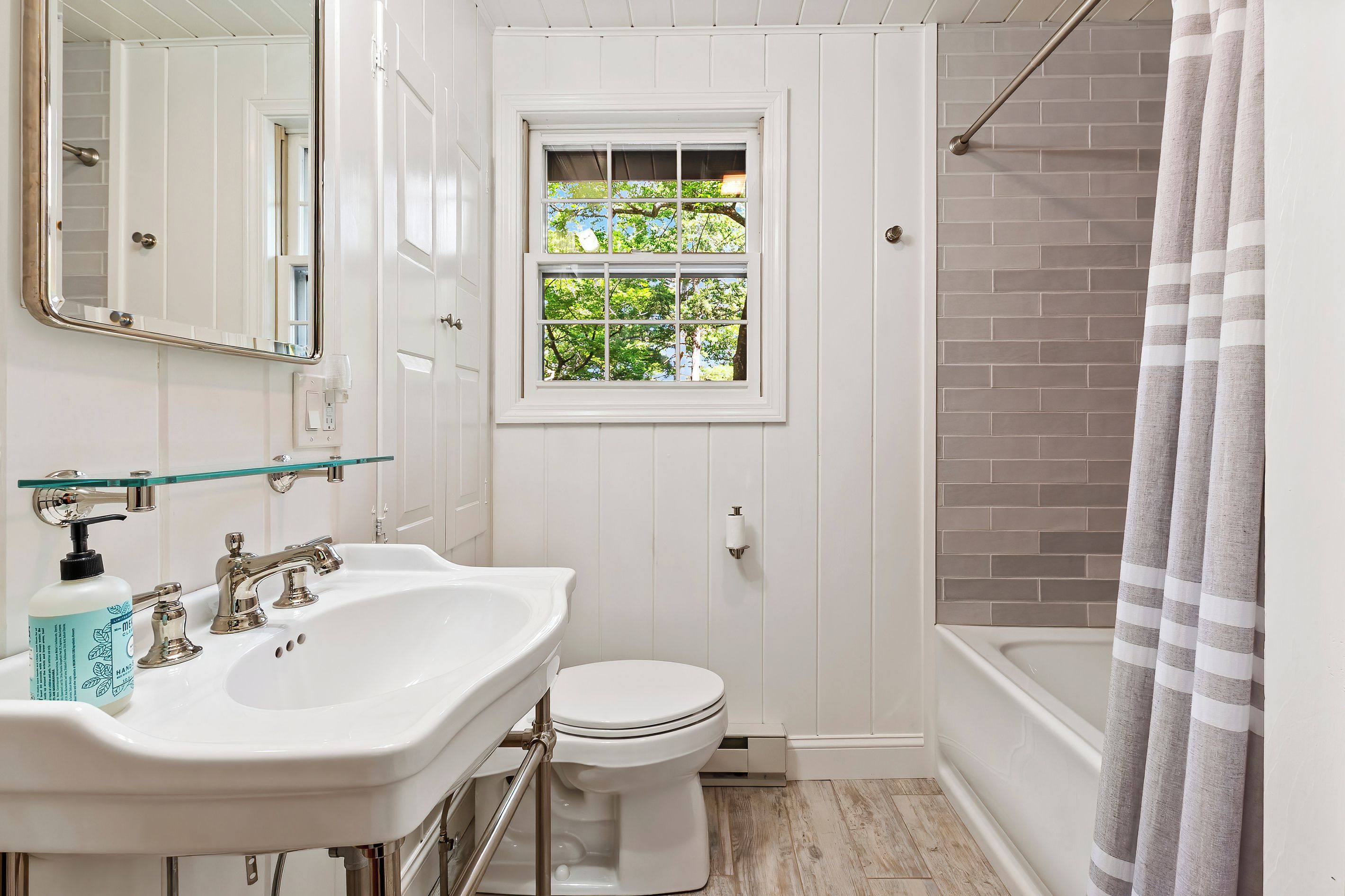 A bathroom with a white sink, toilet, and a window with a view of trees.