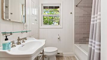 A bathroom with a white sink, toilet, and a window with a view of trees.