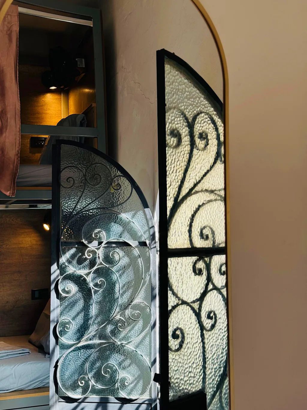 A room with a bed, a wardrobe, and a decorative glass door with intricate patterns.