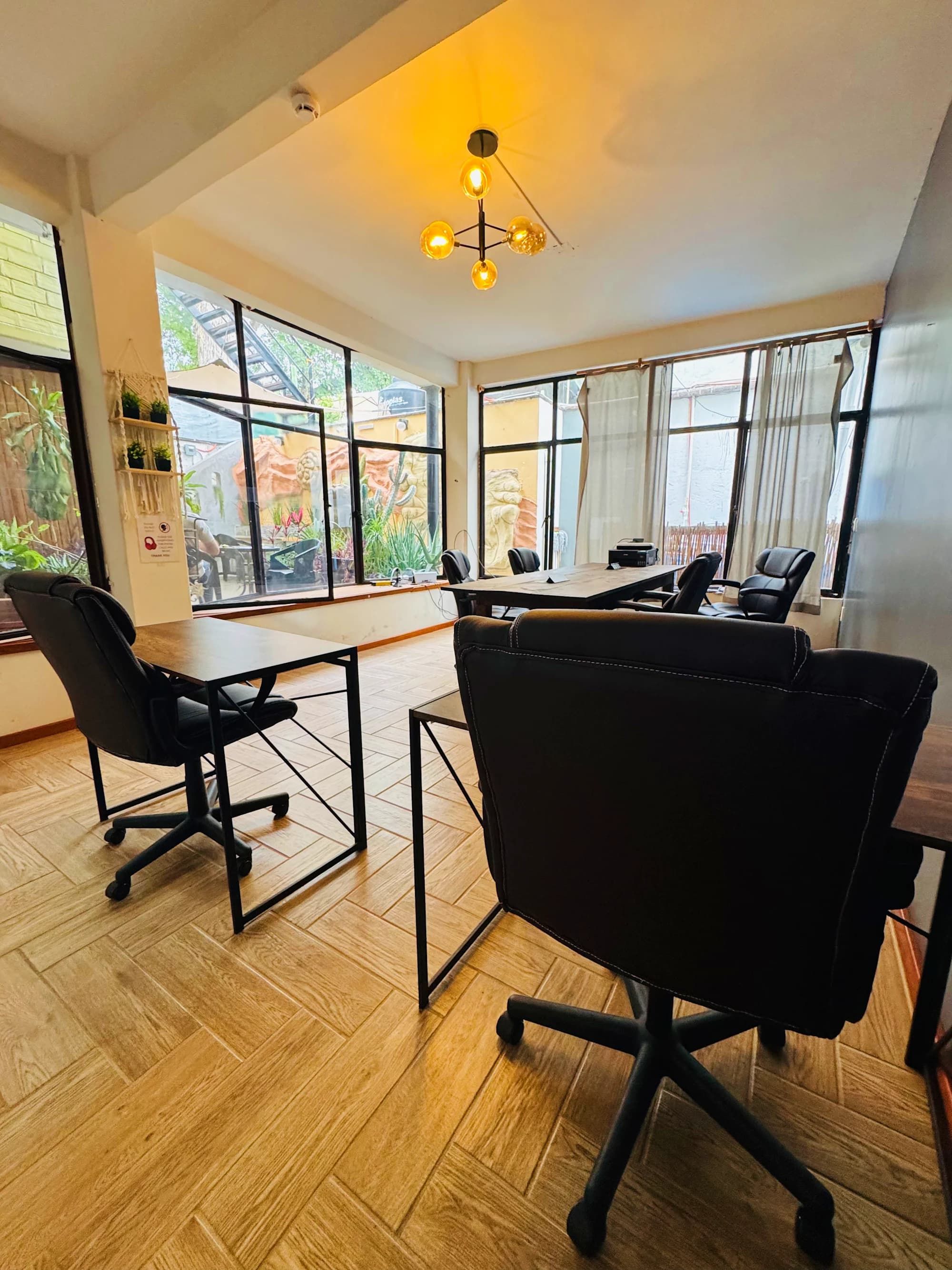 Sala de conferências com uma mesa grande, cadeiras de escritório pretas e um lustre.