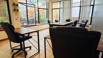 Sala de conferências com uma mesa grande, cadeiras de escritório pretas e um lustre.