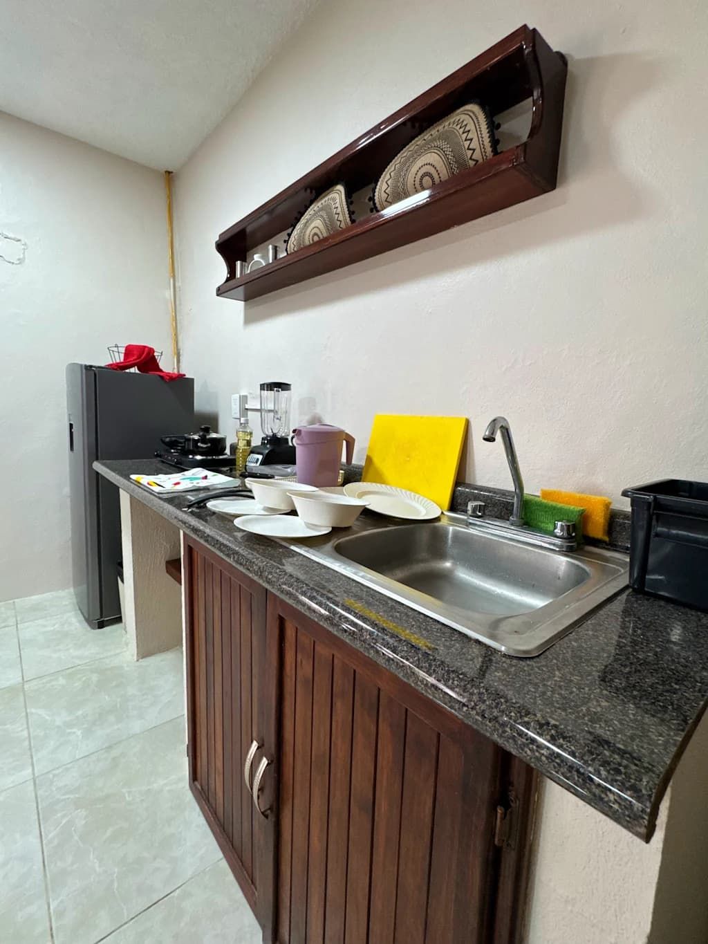 Cozinha com bancada de granito, pia, fogão e prateleira embutida acima da bancada.