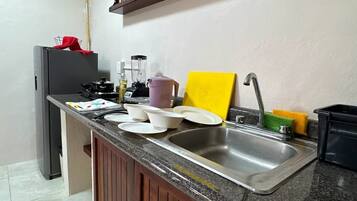 Cozinha com bancada de granito, pia, fogão e prateleira embutida acima da bancada.