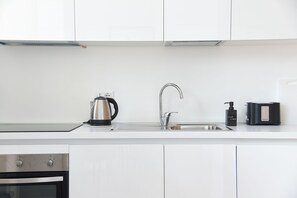 A modern kitchen with a stainless steel kettle, a faucet, and a soap dispenser on the countertop. - Downtown Umberto 74 (Napoli)
