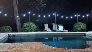 A swimming pool with a tiled deck, surrounded by greenery and white lounge chairs. - Private Tropical Villa • Pool • Near Conchal & Flamingo (Brasilito)