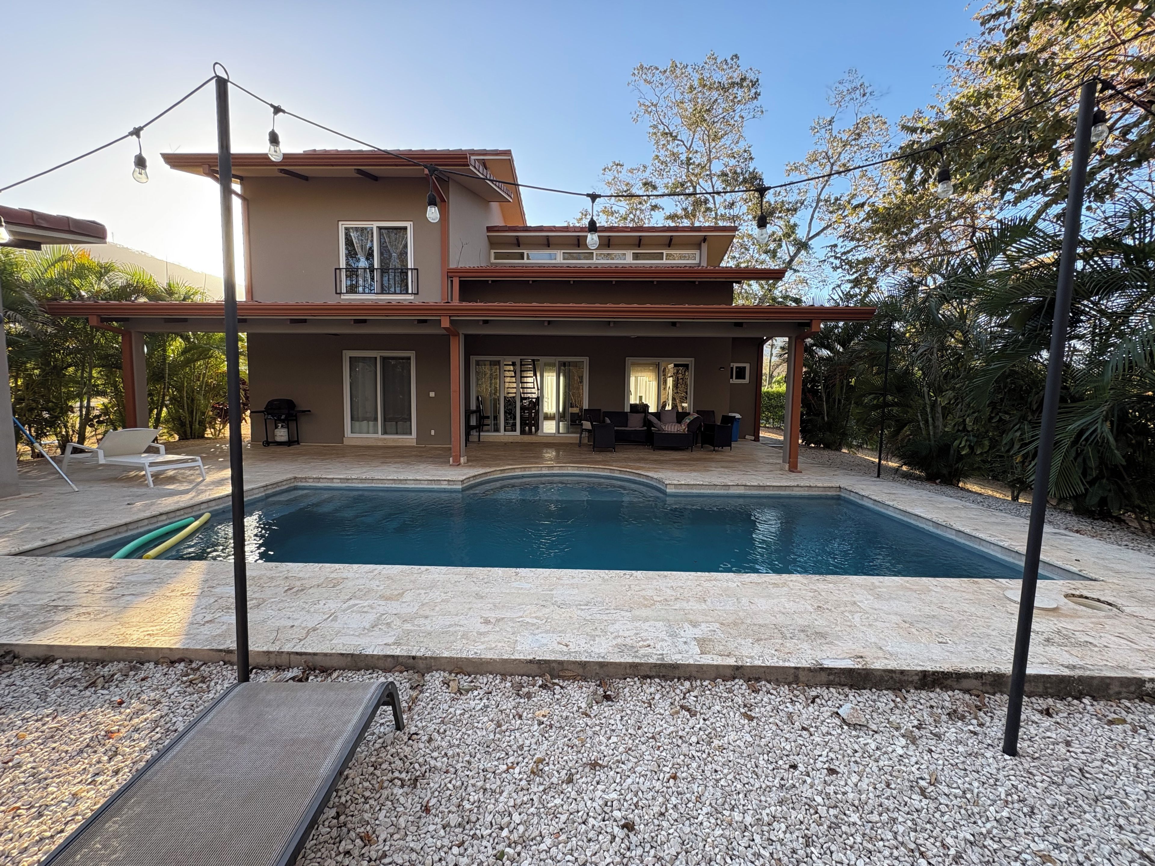 A modern house with a swimming pool, outdoor furniture, and a pergola.