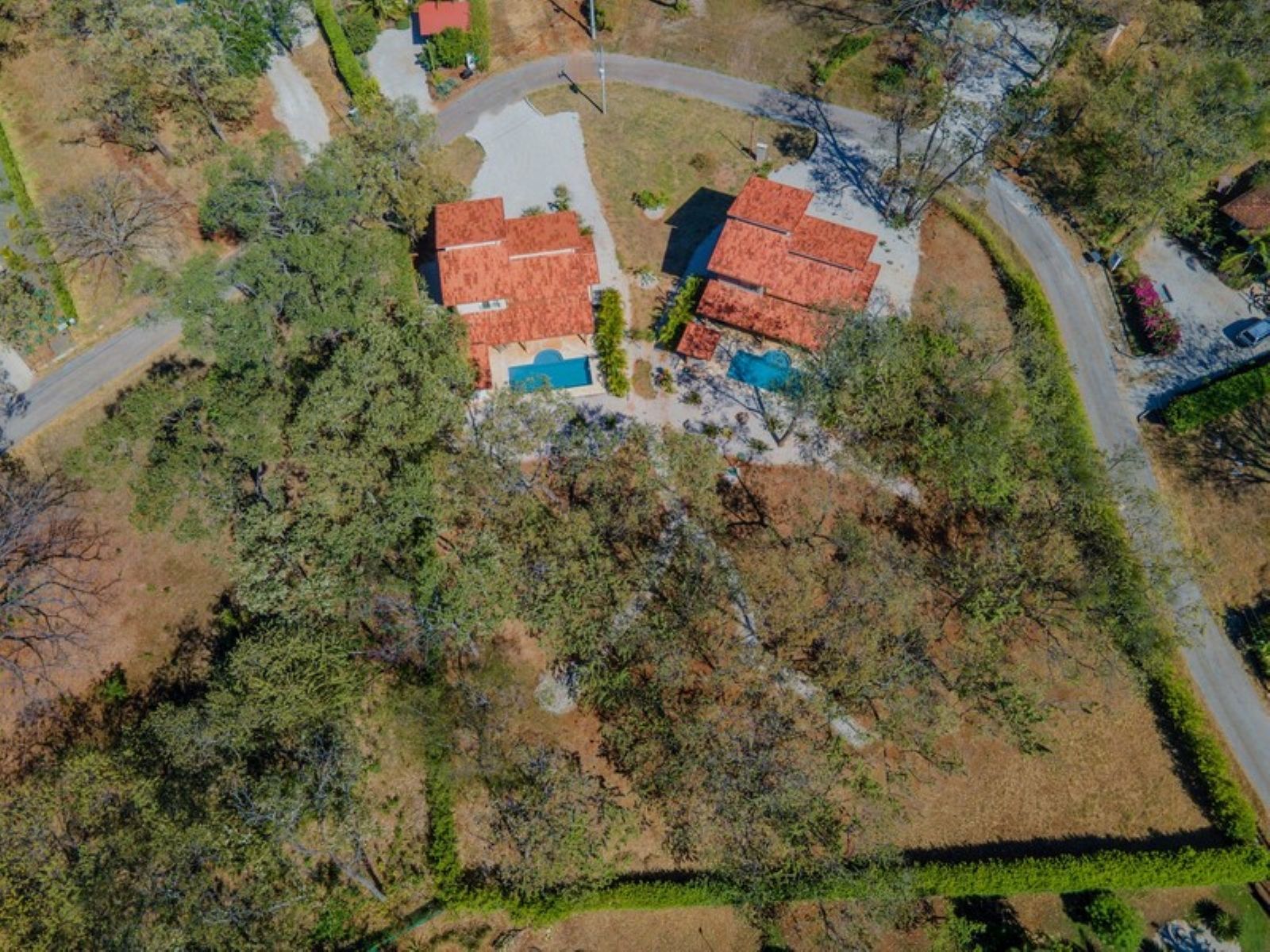 Zona residencial con dos casas, una piscina y una calle.