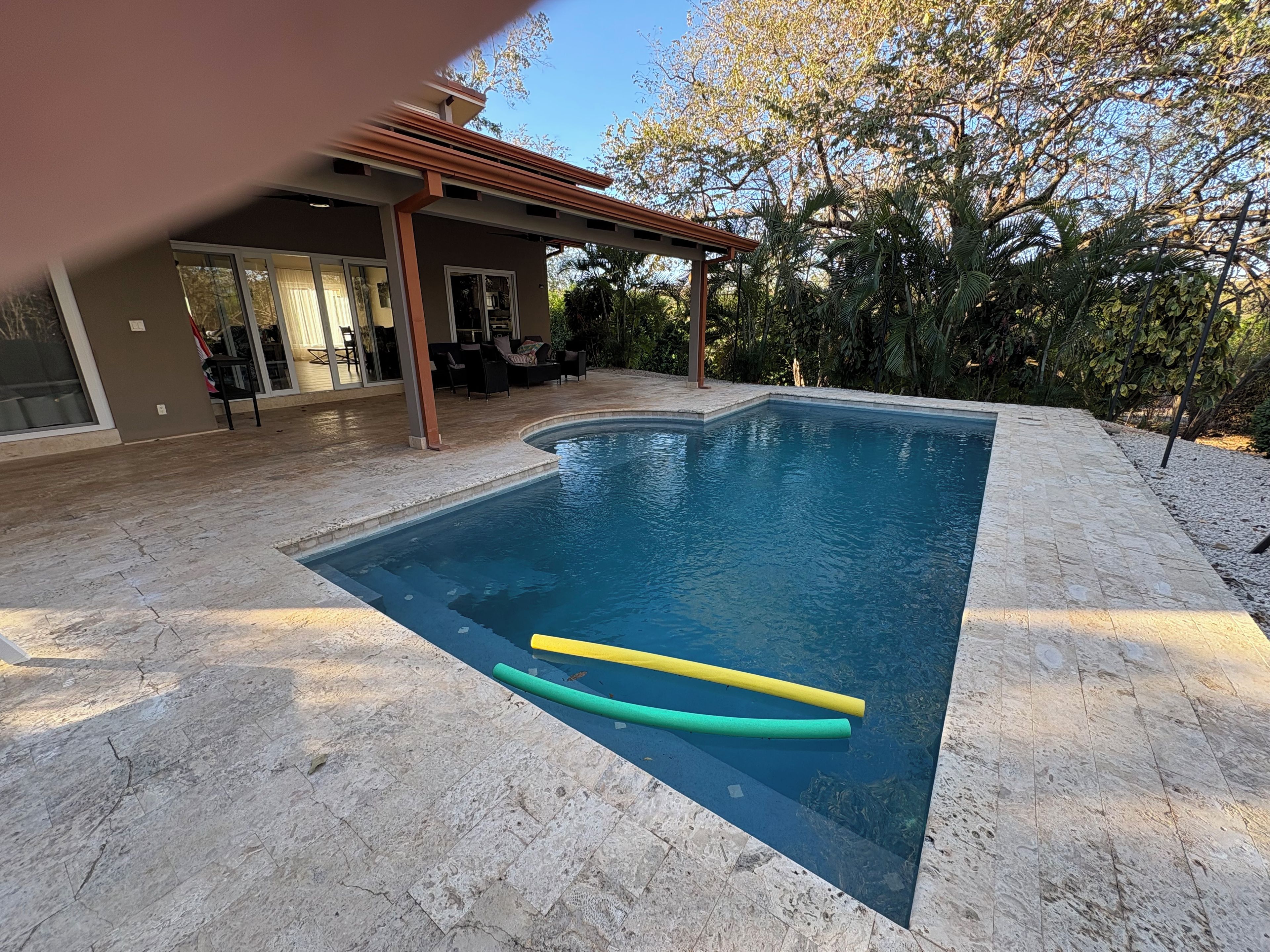 Una piscina con pérgola y mobiliario de exterior.