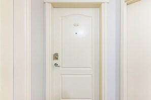Una puerta blanca con teclado numérico, timbre y mirilla.