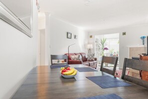 A dining area with a wooden table, a bowl of fruit, and a red leather couch. - Core Downtown condo with 2 bedroom 2  full bathrooms full equipment kitchen (Edmonton)