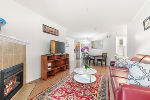 Una sala de estar con chimenea, televisor, mesa de centro y sofá rojo.