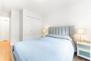 A bedroom with a bed, nightstands, a wardrobe, and a door. - Core Downtown condo with 2 bedroom 2  full bathrooms full equipment kitchen (Edmonton)