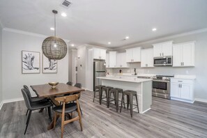 A modern kitchen with white cabinetry, a central island, and bar stools. - Sleeps 24! 8 Bedrooms | Gameroom (Lake Hamilton)