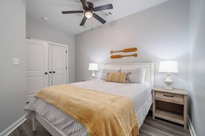 A bedroom with a bed, two bedside tables with lamps, a ceiling fan, and a white door. - Sleeps 24! 8 Bedrooms | Gameroom (Lake Hamilton)