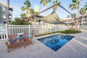 A pool area with a wooden deck, a shaded seating area, and a white fence. - 6 Beds | Pool Steps Away | Private Beach Access (South Padre Island)