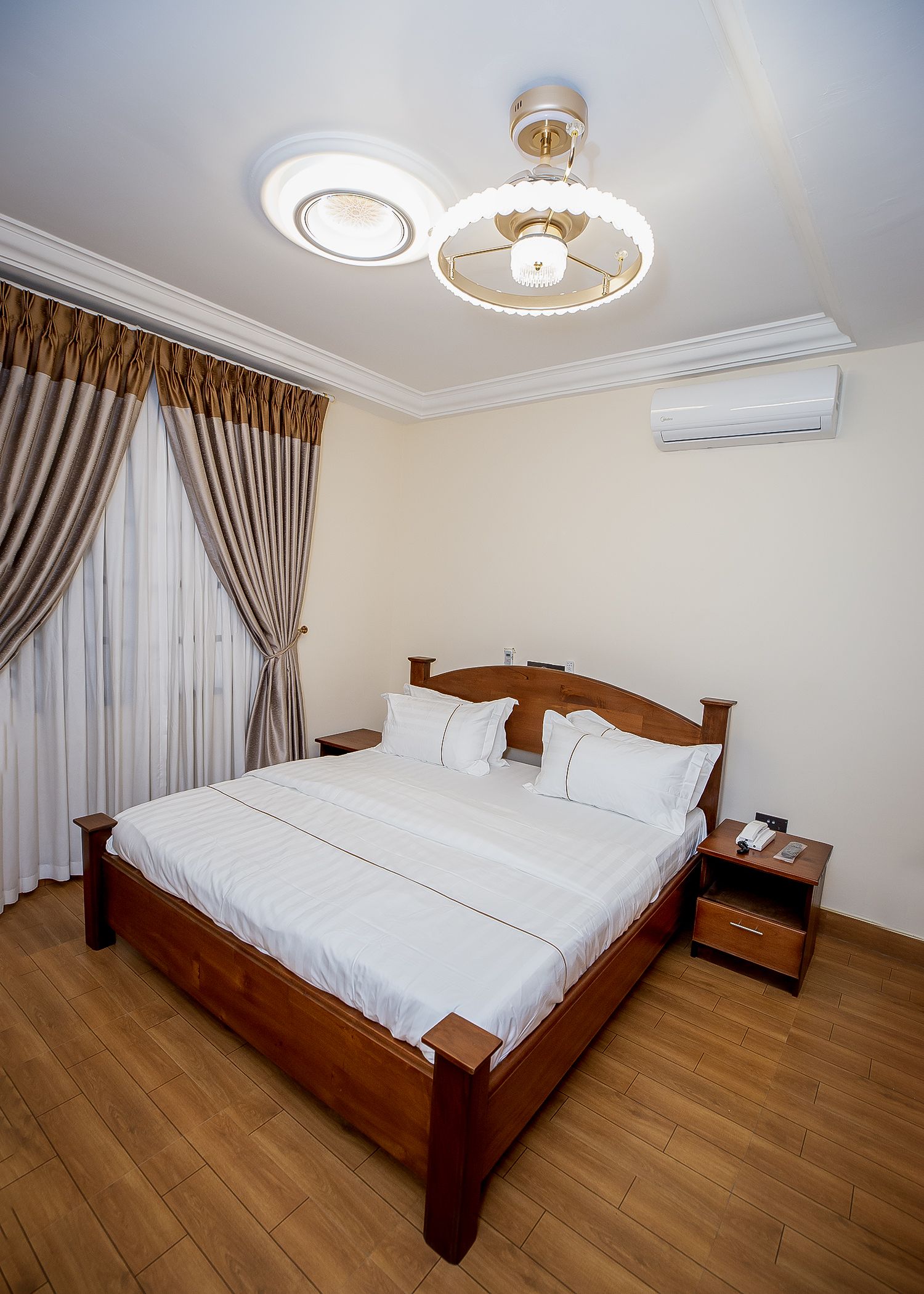 Een slaapkamer met een houten bed, een nachtkastje, een airconditioning en een plafondlamp.