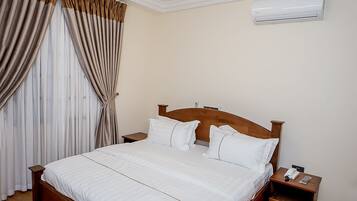 Een slaapkamer met een houten bed, een nachtkastje, een airconditioning en een plafondlamp.