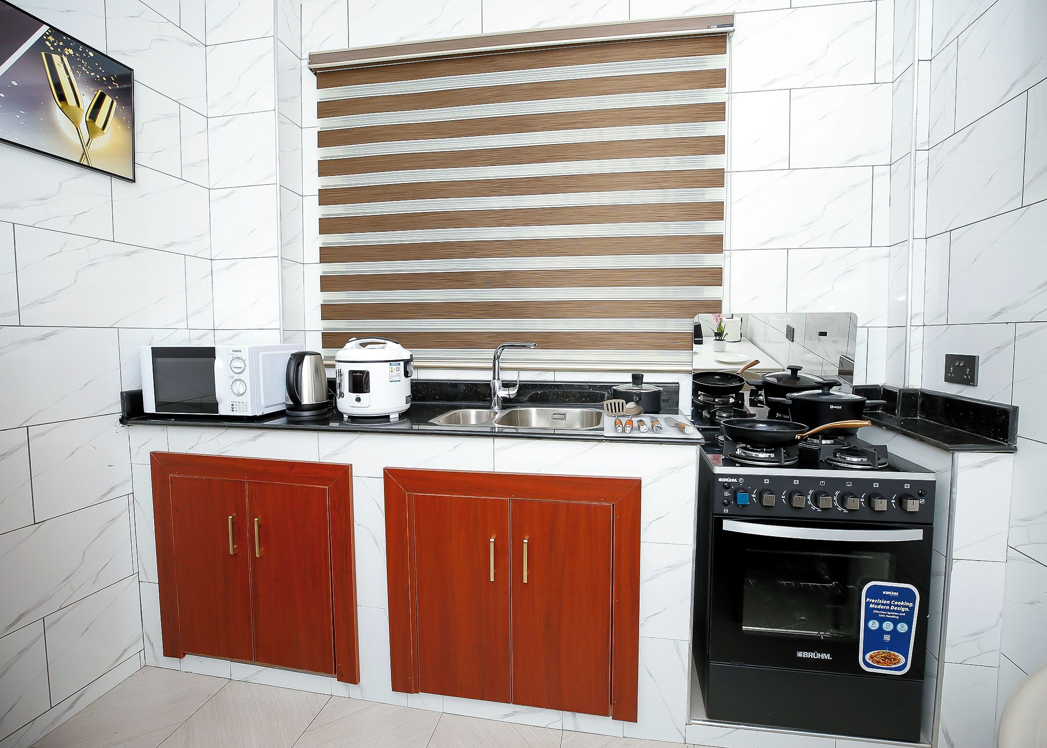 Cocina compacta con microondas, hervidor, estufa y armarios de madera.