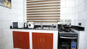 Cocina compacta con microondas, hervidor, estufa y armarios de madera.