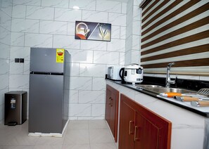 A modern kitchen with a stainless steel refrigerator, a microwave, and a sink. - Charming 1-bedroom apartment in vibrant Kumasi (Kumasi)