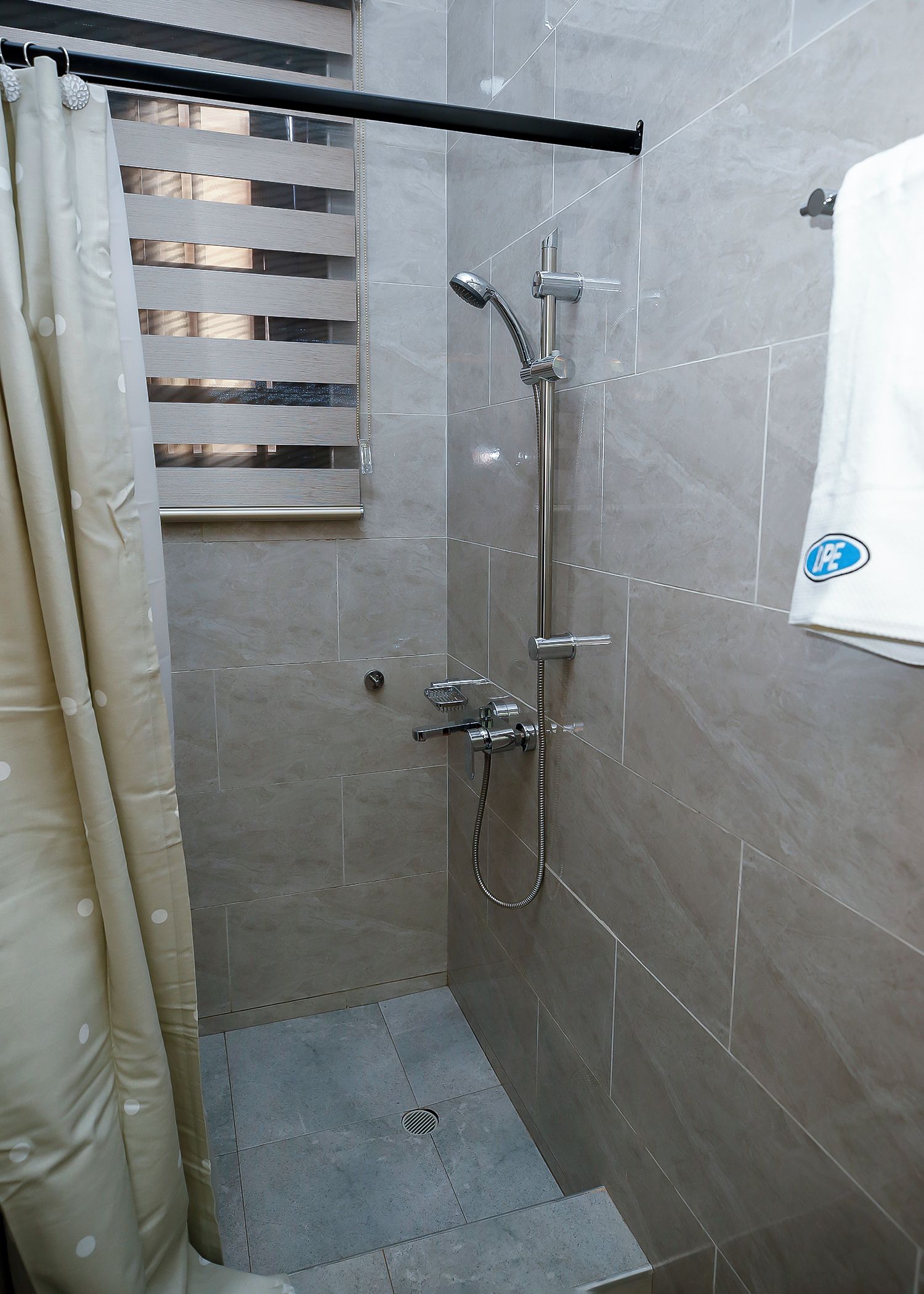 Un espace douche équipé d’un pommeau de douche à main, d’un robinet mural et d’une manette de réglage de la douche.