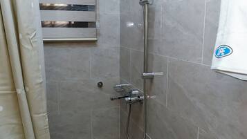 Un espace douche équipé d’un pommeau de douche à main, d’un robinet mural et d’une manette de réglage de la douche.