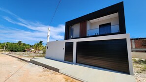 A modern two-story building with a garage and a visible power line. - Mangrove Refuge: A new, high-end home in the Brazilian Caribbean. (Barra Grande)