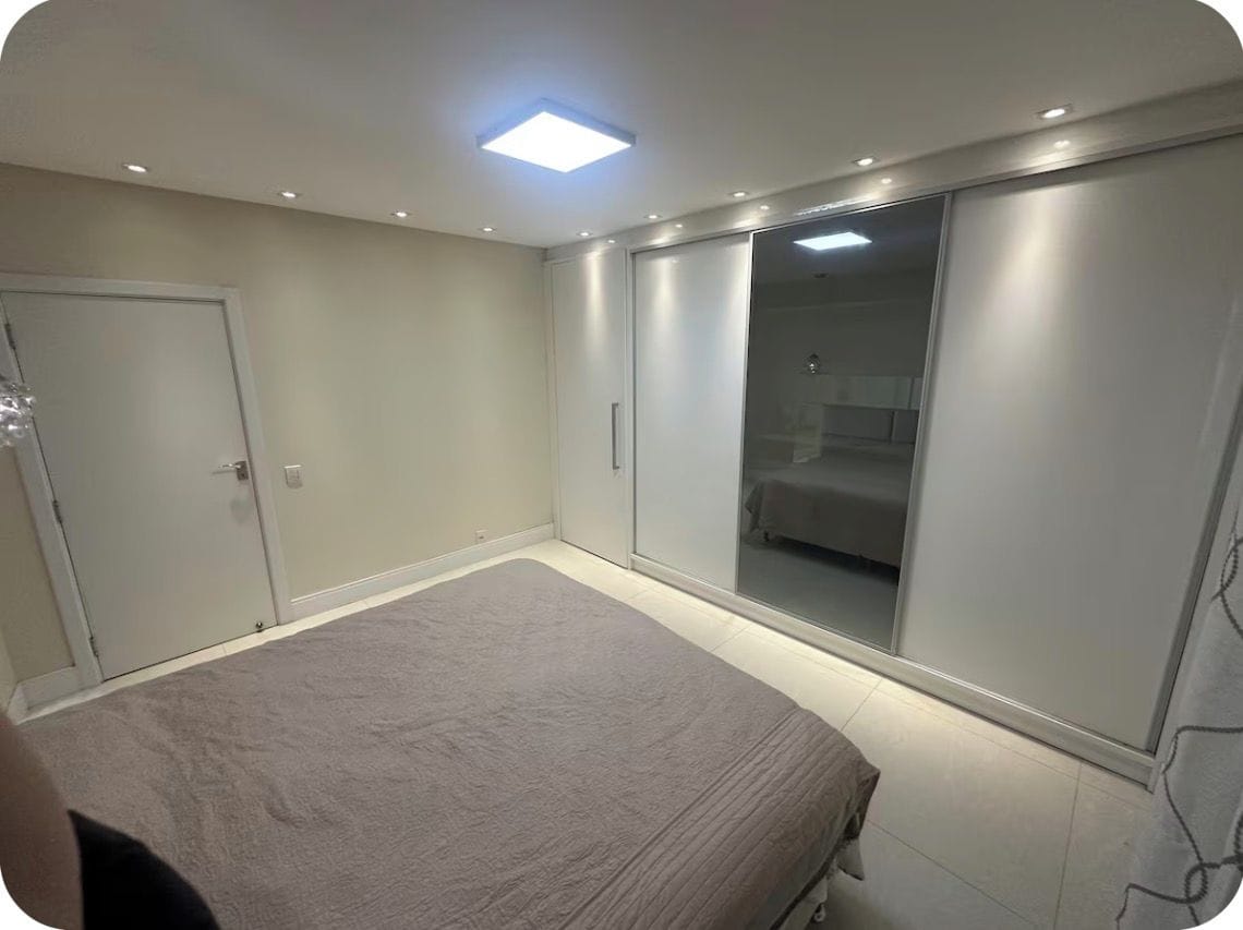 A bedroom with a bed, a wardrobe, and a sliding door closet.
