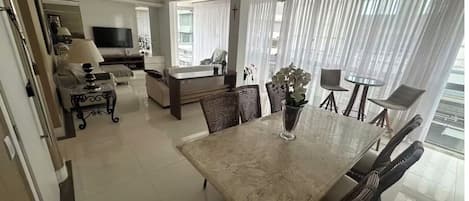 A spacious living area with a dining table, chairs, a TV, and a sofa.