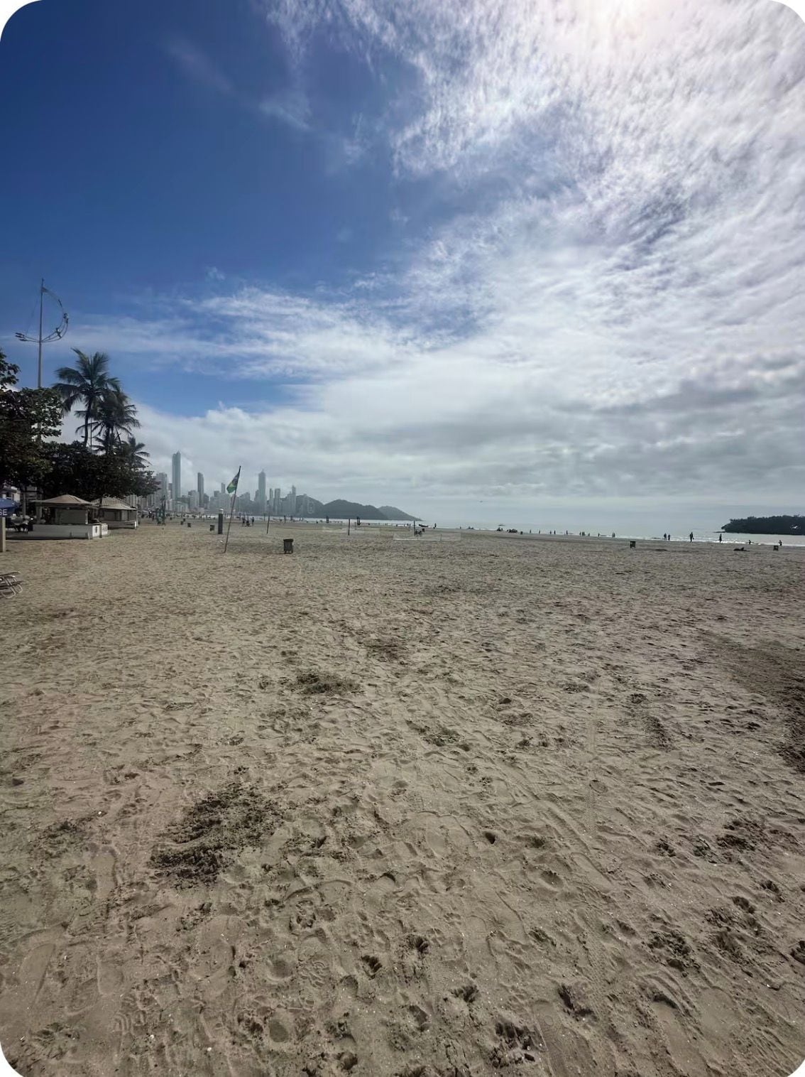 A wide sandy beach with a city skyline in the background.