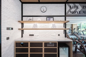 A gym with a white brick wall, a clock, and exercise equipment. - Four Points By Sheraton Guangzhou Huangpu (Guangzhou)